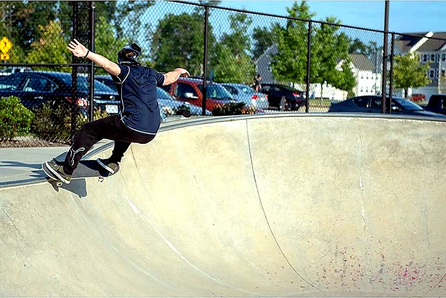 Skateboarder carving across a concrete skate bowl