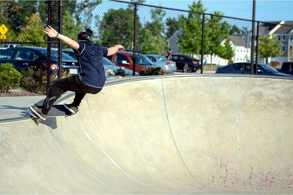 Skateboarder carving across a concrete skate bowl