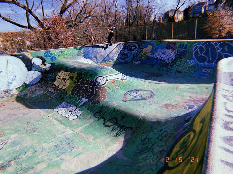 Skate park bowl with graffiti and a skater in the background